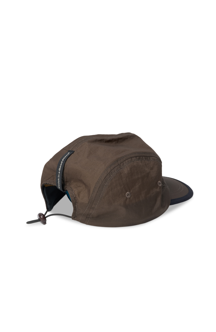 Unisex running cap in Wren Brown. Made in a lightweight (50g/m2) GRS Recycled Polyester. Water repellent, PFC free and adjustable strap. UNNA logo in front and black 