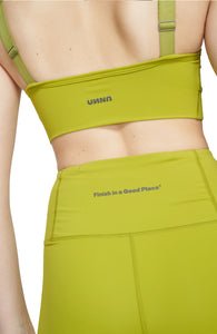 Sports bra in Golden Green with comfortable support, removable padding and adjustable strap. UNNA logo on the back. Made in Econyl.